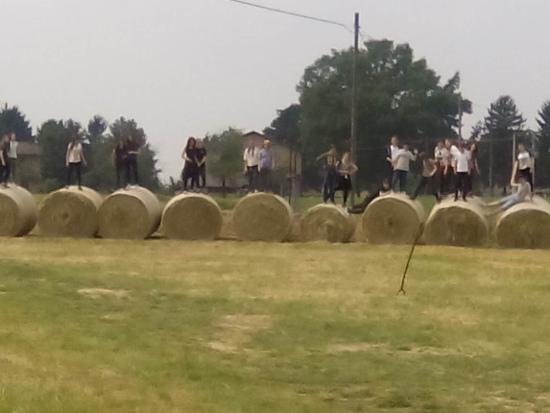 Ragazzi di una scuola media si divertono a saltare tra le rotoballe