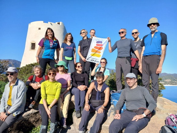 Gruppo di camminatori con bandiera Compagnia dei Cammini, davanti al mare sul Cammino 100 Torri